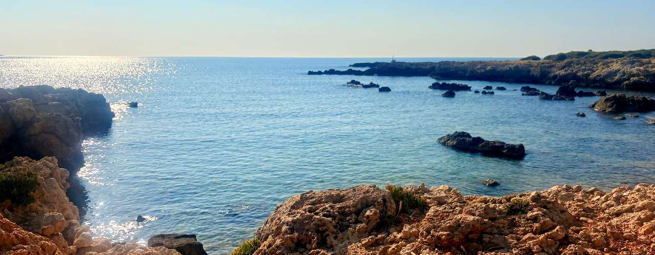 Spiaggia di Ognina con scogli e mare turchese vicino a Ortigia